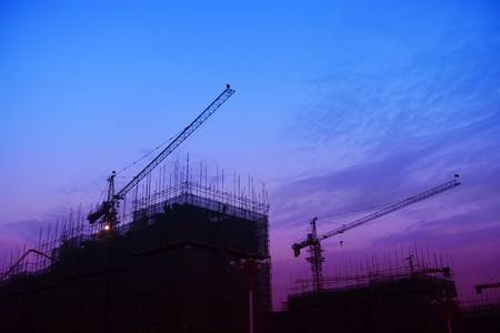 The crane on the construction site in the sunsetの写真素材