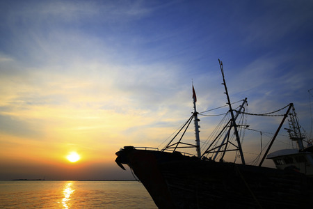 Fishing boats silhouetted against the setting sunの写真素材