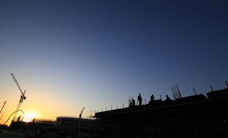 Cranes at work, silhouetted on construction sites