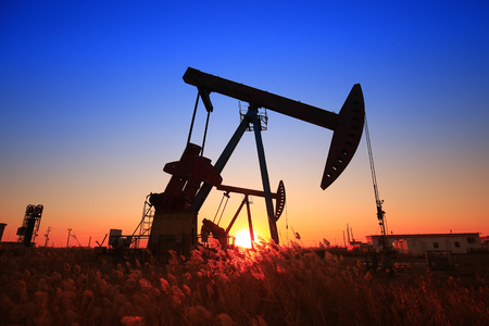 The oil pump in an oil field during sunsetの写真素材