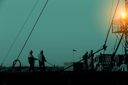 Oil pump workers working in an oil field during sunsetのeditorial素材