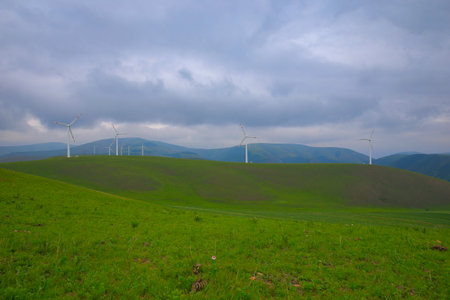 Windmills aerial view. Renewable energy. Large wind turbines with blades in field bright Green...