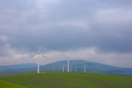 Windmills aerial view. Renewable energy. Large wind turbines with blades in field bright Green grassland.の写真素材