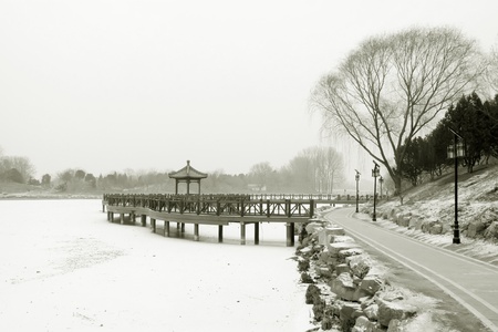 Chinese traditional style wooden bridge in the snow in a parkの写真素材