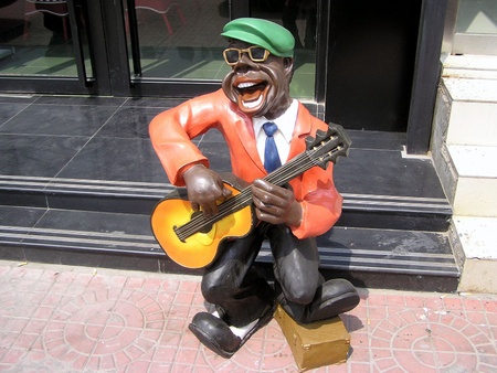 play an instrument of character sculpture in front of a restaurant door 