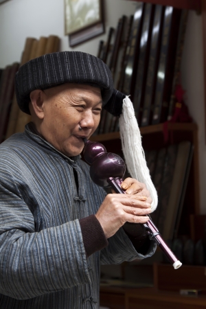Phoenix County, April 15  Old man playing bottle gourd silk on April 15, 2012, Phoenix County, Hunan Province, Chinaのeditorial素材