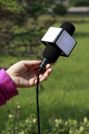 hand taking microphone in green background, closeup of photoの写真素材