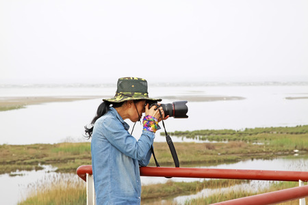 QINHUANGDAO CITY- JUNE 1: A female photographer was photographing in a wetland park, June 1, 2014, Qinghuangdao city, Hebei Province, Chinaのeditorial素材