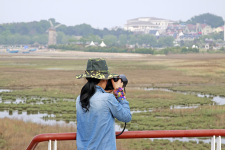 QINHUANGDAO CITY- JUNE 1: A female photographer was photographing in a wetland park, June 1, 2014, Qinghuangdao city, Hebei Province, China
のeditorial素材