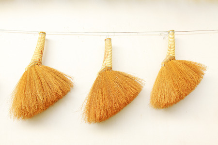 Broom hung on the white wall, closeup of photoの写真素材