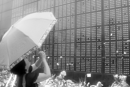 Tangshan City, July 28: A woman taking sunshade before the Tangshan Earthquake Memorial Wall, looking for the names of relatives died in the earthquake on July 28, 2012, Tangshan City, Hebei Province, China.のeditorial素材
