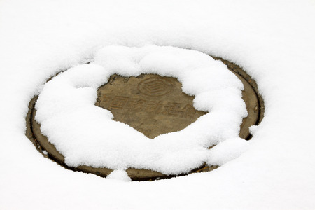 sewer metal cover in the snow, closeup of photoのeditorial素材