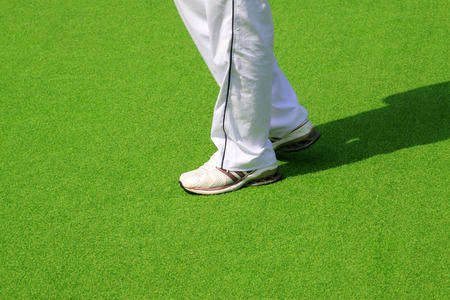 White shoes and trousers in green plastic stadium, closeup of photoのeditorial素材