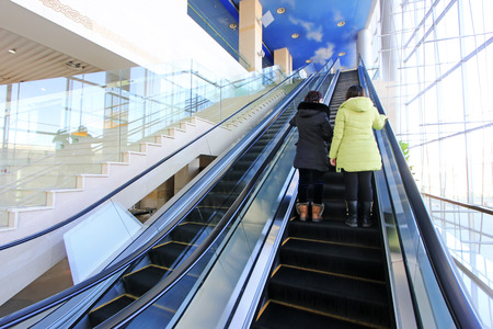 tourists on the escalator in a shop, closeup of photo