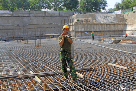 Luannan County - August 21: construction workers handling reinforced bar in the construction site, on August 21, 2015, luannan county, hebei province, Chinaのeditorial素材