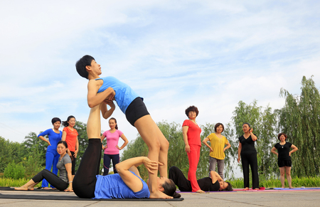 Tangshan - July 3 2016: women doing yoga exercise in the park, tangshan city, hebei province, Chinaのeditorial素材