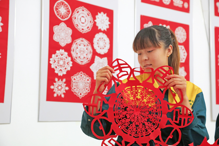 Luannan county - May 13: a girl watching paper-cut works, on May 13, 2016, Luannan county, hebei province, China.のeditorial素材
