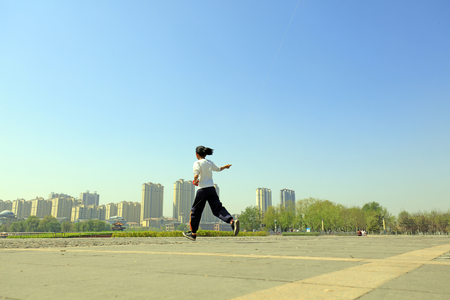 A Chinese girl flying a kite in the squareのeditorial素材