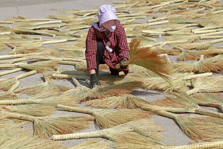 Luannan County - May 23, 2018: A woman worker is drying the broom, Luannan County, Hebei Province, Chinaのeditorial素材