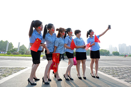 Luannan County, China-July 12, 2019: Ladies are taking pictures with the national flag in hand, Luannan County, Hebei Province, Chinaのeditorial素材