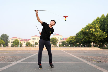 Luannan County, China-July 12, 2019: People wave Diabolo to exercise in parks, Luannan County, Hebei Province, China. Diabolo is one of the traditional Chinese folk fitness ways.のeditorial素材