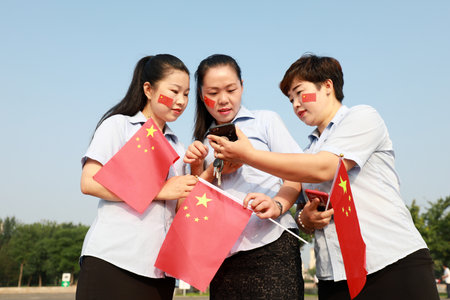 Luannan County, China-July 12, 2019: Ladies are taking pictures with the national flag in hand, Luannan County, Hebei Province, Chinaのeditorial素材