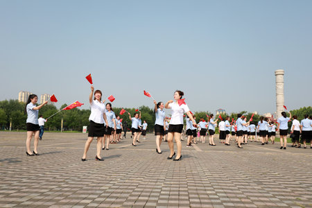 Luannan County, China-July 12, 2019: Ladies walking with Chinese flag in the park, Luannan County, Hebei Province, Chinaのeditorial素材