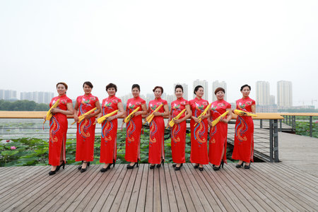 Luannan County, China-July 9, 2019: Women in red cheongsams are performing in a walk show, Luannan County, Hebei Province, Chinaのeditorial素材