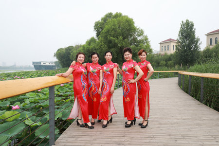 Luannan County, China-July 9, 2019: Women in red cheongsams are performing in a walk show, Luannan County, Hebei Province, Chinaのeditorial素材