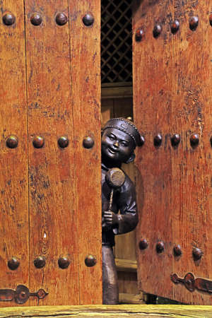 Tangshan City, China-December 22, 2020: Ancient Chinese children's bronze sculptures in a crack in the door are in an exhibition hall, Tangshan City, Hebei Province, Chinaのeditorial素材