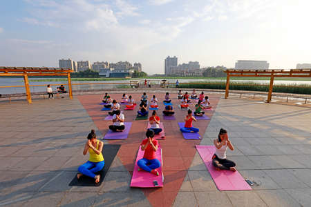 LUANNAN COUNTY, China-June 30, 2018: Women are practicing outdoor yoga in a park, LUANNAN COUNTY, Hebei Province, Chinaのeditorial素材