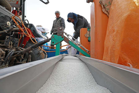 LUANNAN COUNTY, Hebei Province, China-March 12, 2020: The farmer is adding fertilizer to the planter in the field.のeditorial素材