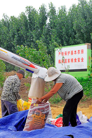 LUANNAN COUNTY, China-June 19, 2018: farmers use harvesters to harvest wheat in fields, LUANNAN COUNTY, Hebei Province, Chinaのeditorial素材