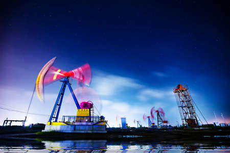 Oil pumping machinery in operation, crude oil extraction scene in the night, North Chinaの写真素材