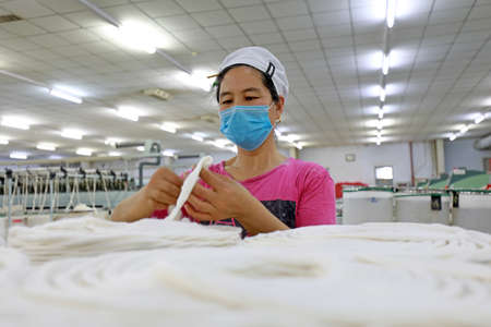 LUANNAN COUNTY, Hebei Province, China-March 18, 2020: The female worker is busy on the production line in a spinning factory.のeditorial素材