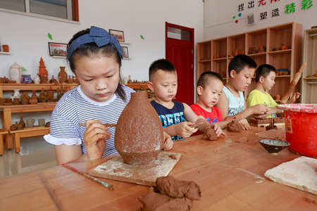 LUANNAN COUNTY, China-July 20, 2018: The girl is concentrating on making ceramic works, LUANNAN COUNTY, Hebei Province, Chinaのeditorial素材