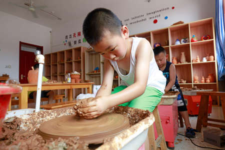 LUANNAN COUNTY, China-July 20, 2018: The girl is concentrating on making ceramic works, LUANNAN COUNTY, Hebei Province, Chinaのeditorial素材