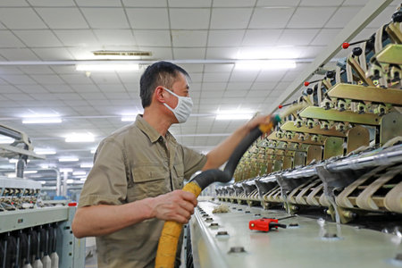 LUANNAN COUNTY, Hebei Province, China-March 18, 2020: The workers are repairing the spinning machinery in the factory.のeditorial素材