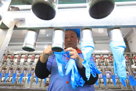 LUANNAN COUNTY, China-November 6, 2018: Water pressure test of medical grade nitrile gloves by female workers, LUANNAN COUNTY, Hebei Province, Chinaのeditorial素材