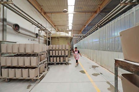 LUANNAN COUNTY, Hebei Province, China-August 11, 2020: A woman worker walked past the semi-finished sanitary ware workshopのeditorial素材