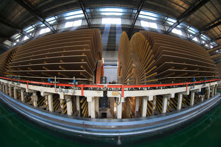 Workers control machinery to produce plates on the production line