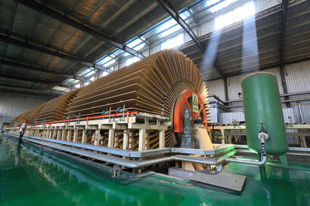 Workers control machinery to produce plates on the production lineのeditorial素材