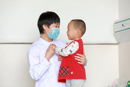 LUANNAN COUNTY, Hebei Province, China-May 11, 2020: A female nurse is taking care of a child patient.のeditorial素材