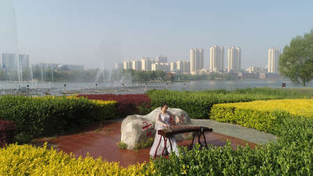 LUANNAN COUNTY, Hebei Province, China-May 10, 2020: A girl is playing zither in the park.のeditorial素材