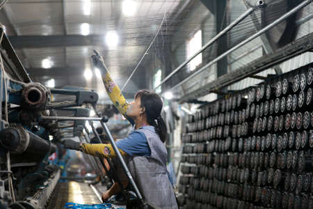 LUANNAN COUNTY, Hebei Province, China-August 28, 2020: The workers are working on a mechanical fishing net in a net factoryのeditorial素材