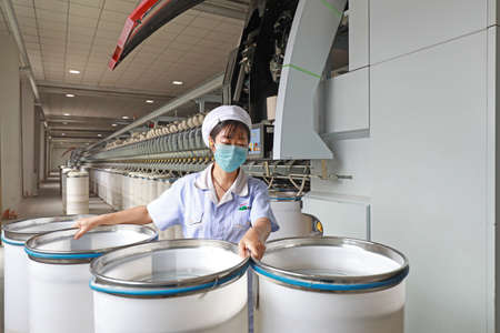 LUANNAN COUNTY, Hebei Province, China-July 17, 2020: The woman worker carries the plastic barrel of...