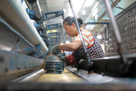LUANNAN COUNTY, Hebei Province, China-August 28, 2020: The workers are working on a mechanical fishing net in a net factoryのeditorial素材