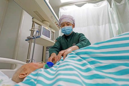 LUANNAN COUNTY, Hebei Province, China-May 11, 2020: A female nurse is taking care of the patient in the intensive care unit.のeditorial素材