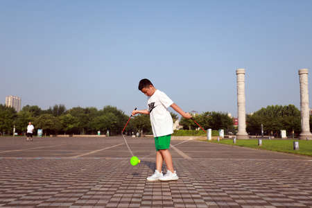 LUANNAN COUNTY, Hebei Province, China-August 1, 2020: A teenager is shaking diabolo to keep fit in the squareのeditorial素材