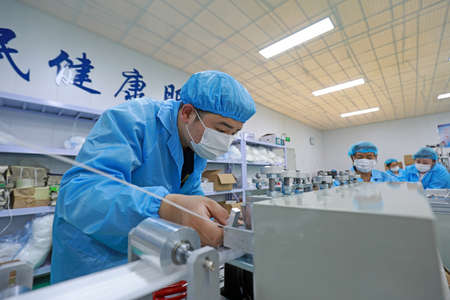 LUANNAN COUNTY, Hebei Province, China-April 15, 2020: Workers are busy on the production line in a Medical mask factory.のeditorial素材